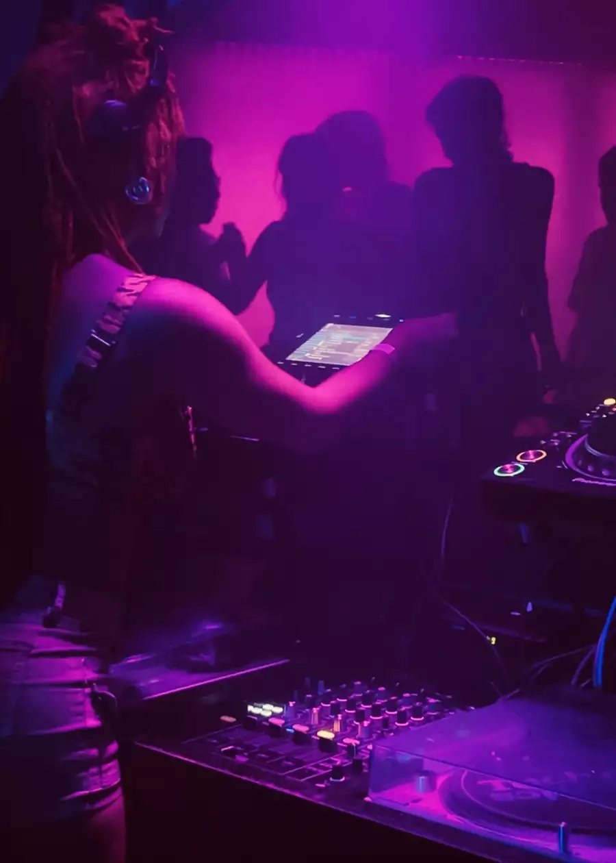 A DJ behind decks while people dance