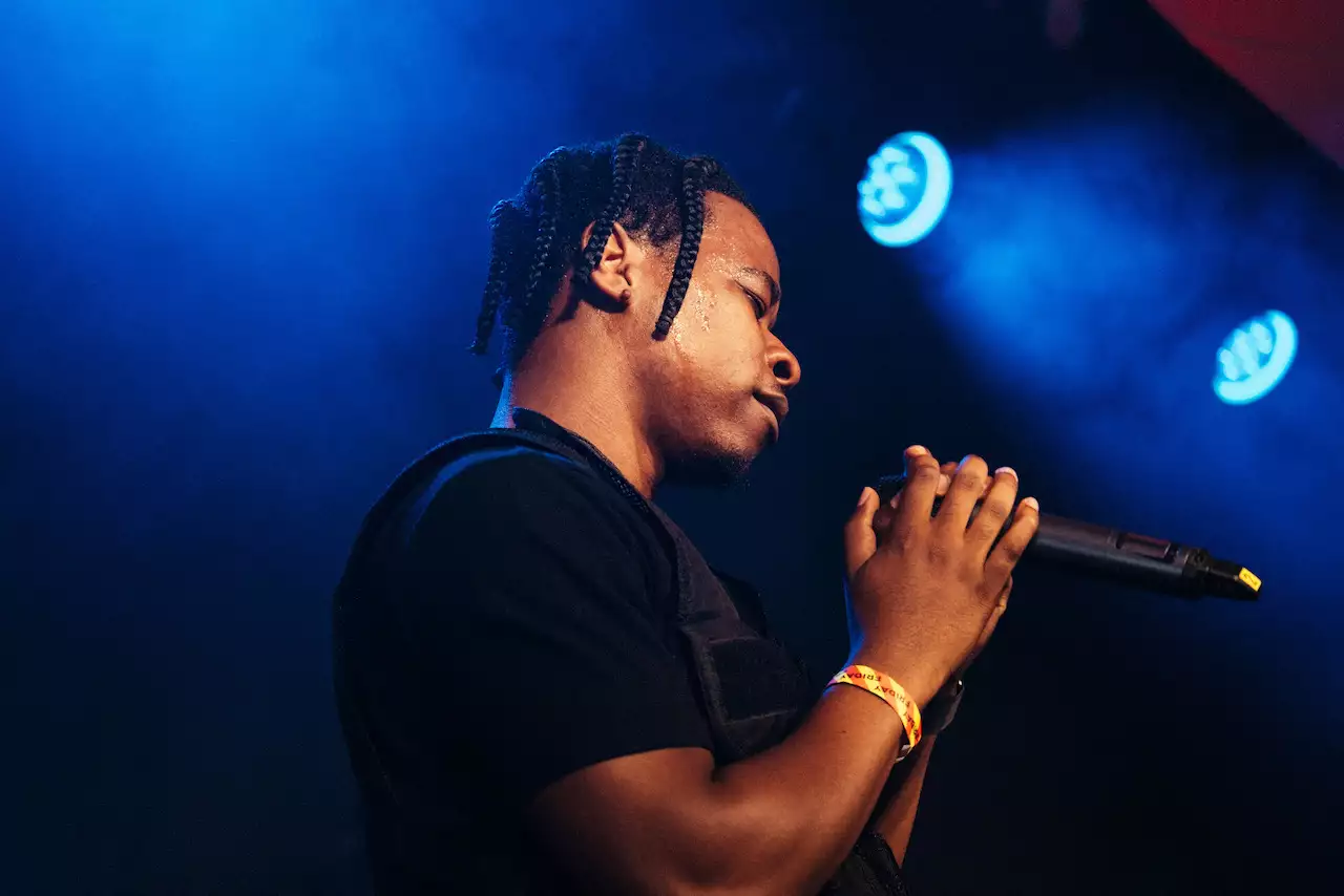 Photo of a person singing into a microphone on stage