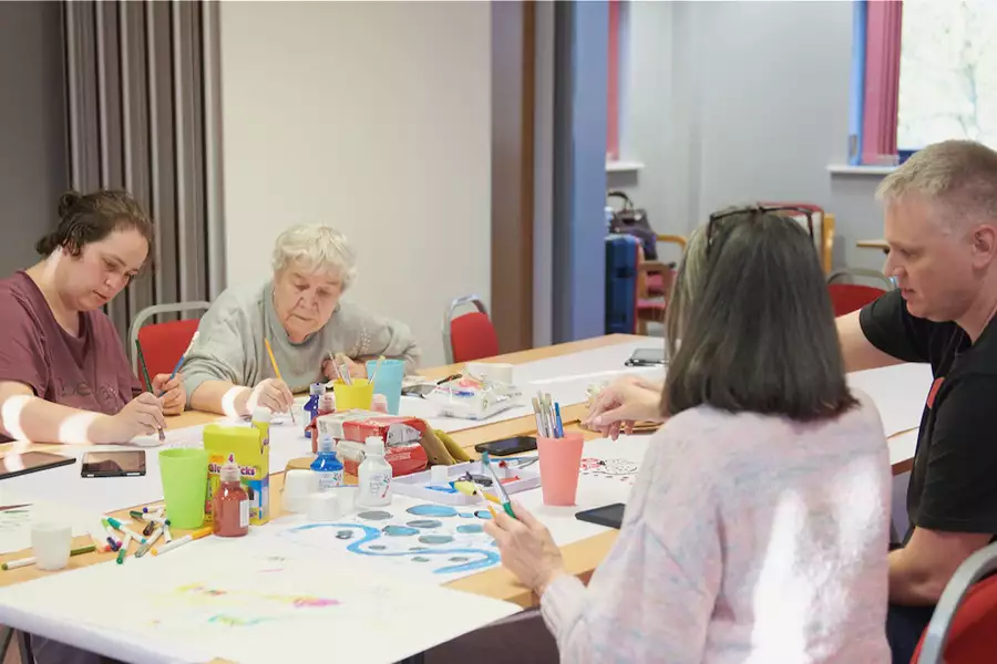 Photo of four people sat at a table painting