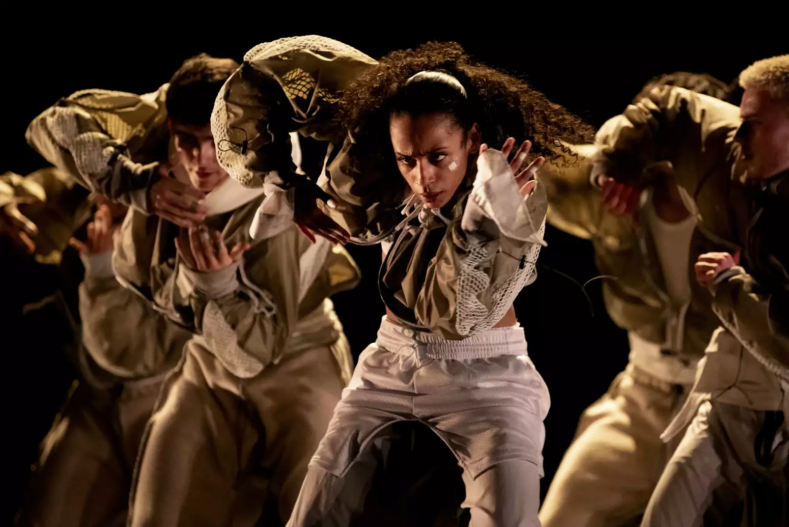 A group of five dancers on stage during Boy Blue, wearing white tracksuits, with serious expressions on their faces