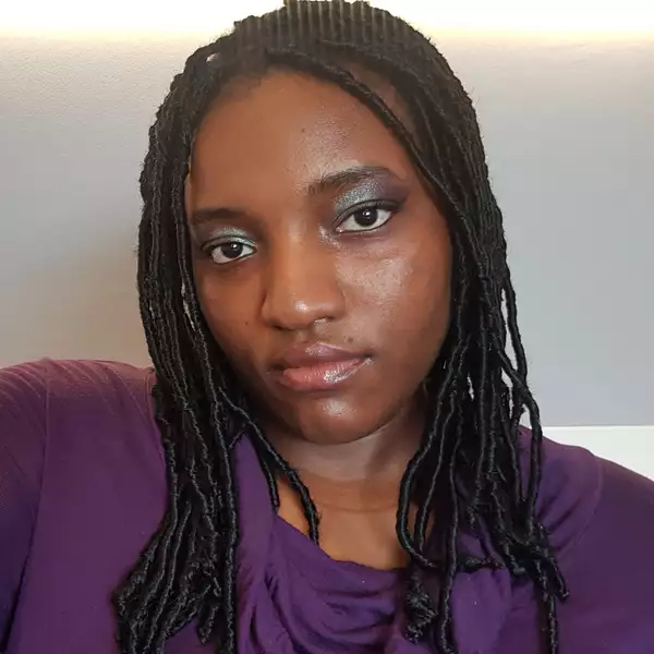 Square headshot of Anita Ezeh wearing a purple top and glittery eyeshadow