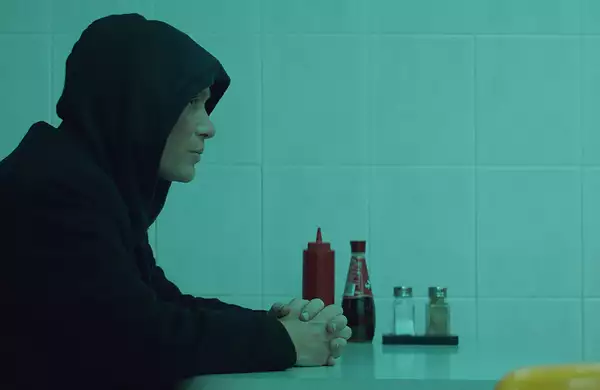 All this this unreal time thumbnail of side view of man in a hoodie sat at a table