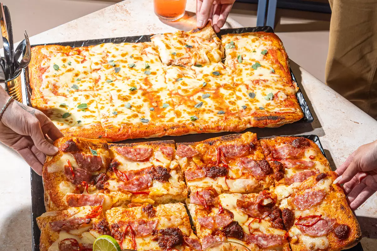 A pepperoni pizza and margherita pizza and three cocktails on a table