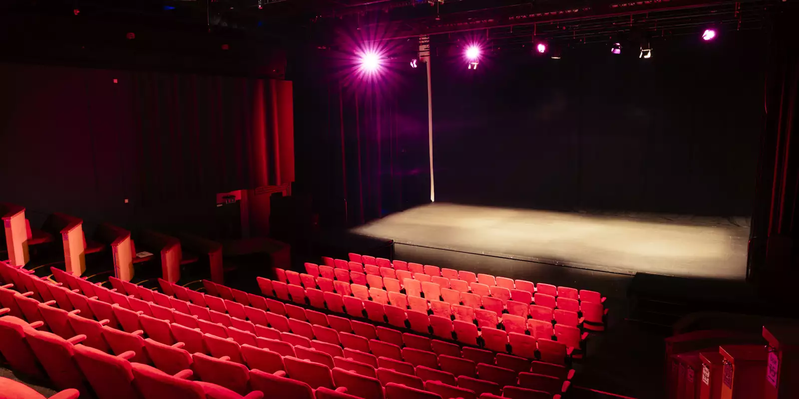 A performance space at Contact. Rows of red seats overlook a stage.