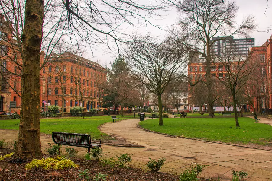 Benches and greenery in Sackville Gardens overlooked by red brick buildings