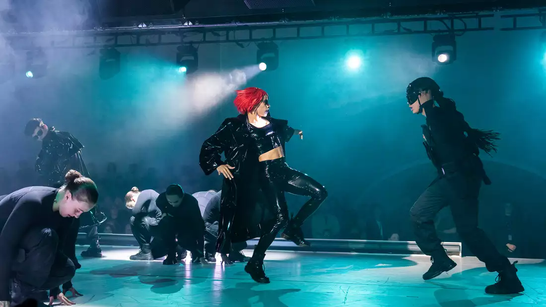 Dancers wearing black perform on stage for Free Your Mind with blue lighting