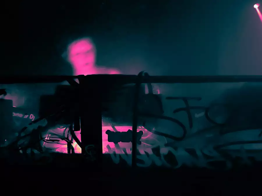 A person DJs in a booth decorated with graffiti and stickers