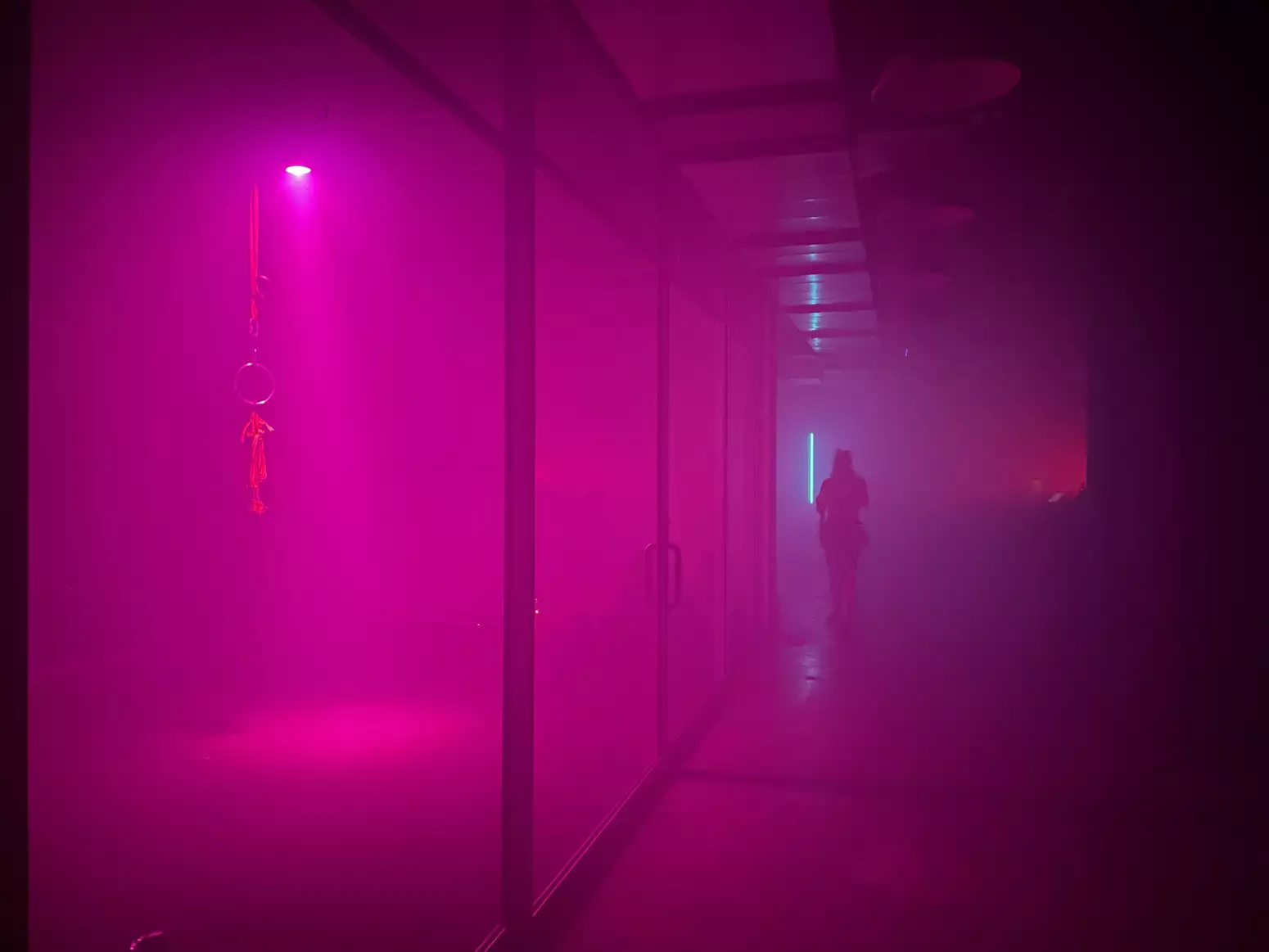 A corridor bathed in pink light with a person at the far end