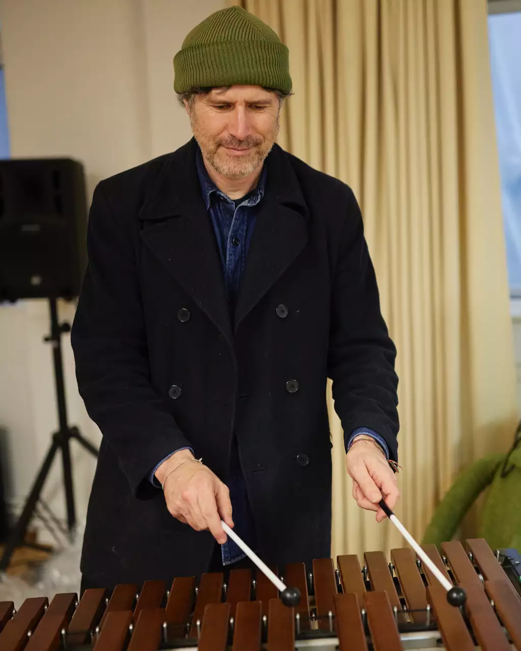 Gruff Rhys playing xylophone in a green hat