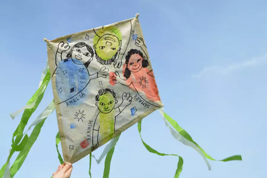 A hand drawn kite with green paper ribbons in the sky