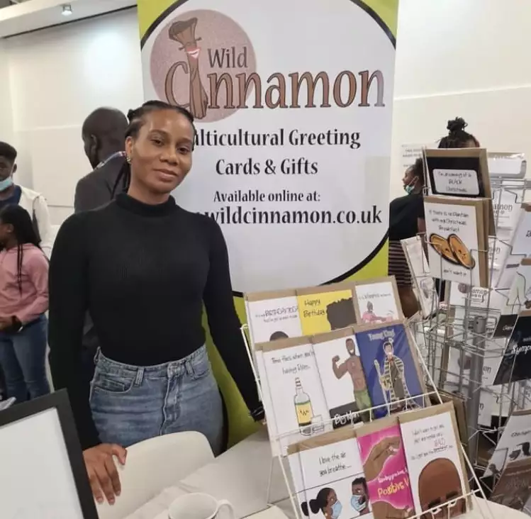 A trader smiling in front of a stand that reads 'Wild Cinnamon'