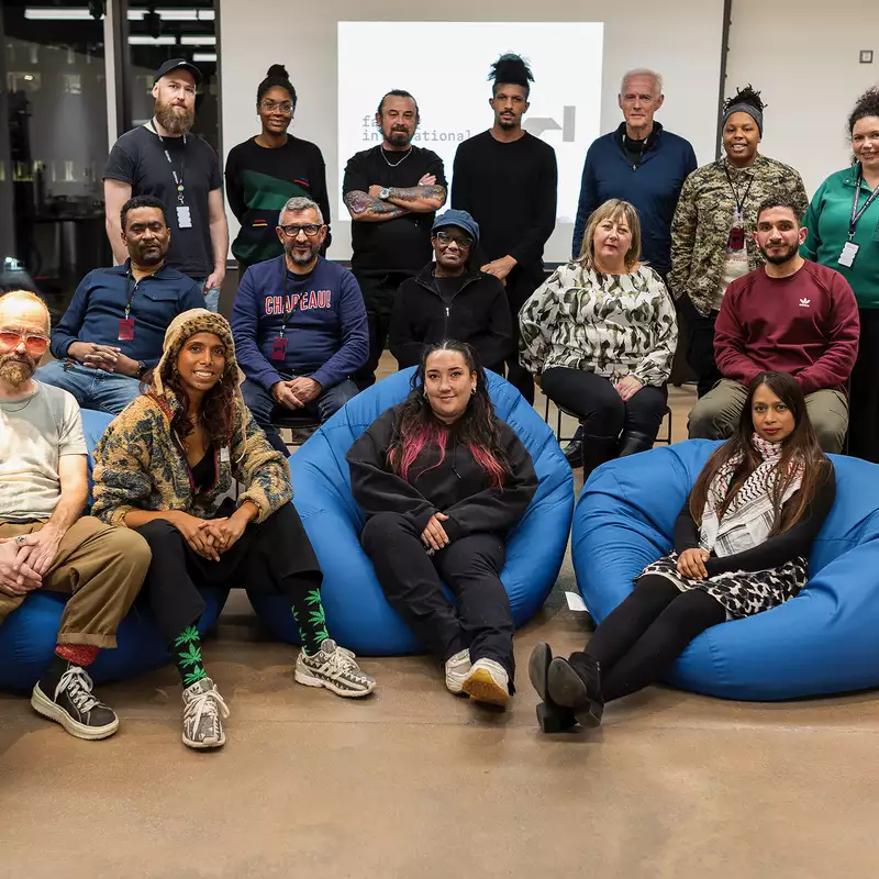 Group photo of Fusion Factory and BRiGHTBLACK. Some people are stood up; others are sat on three blue beanbags.