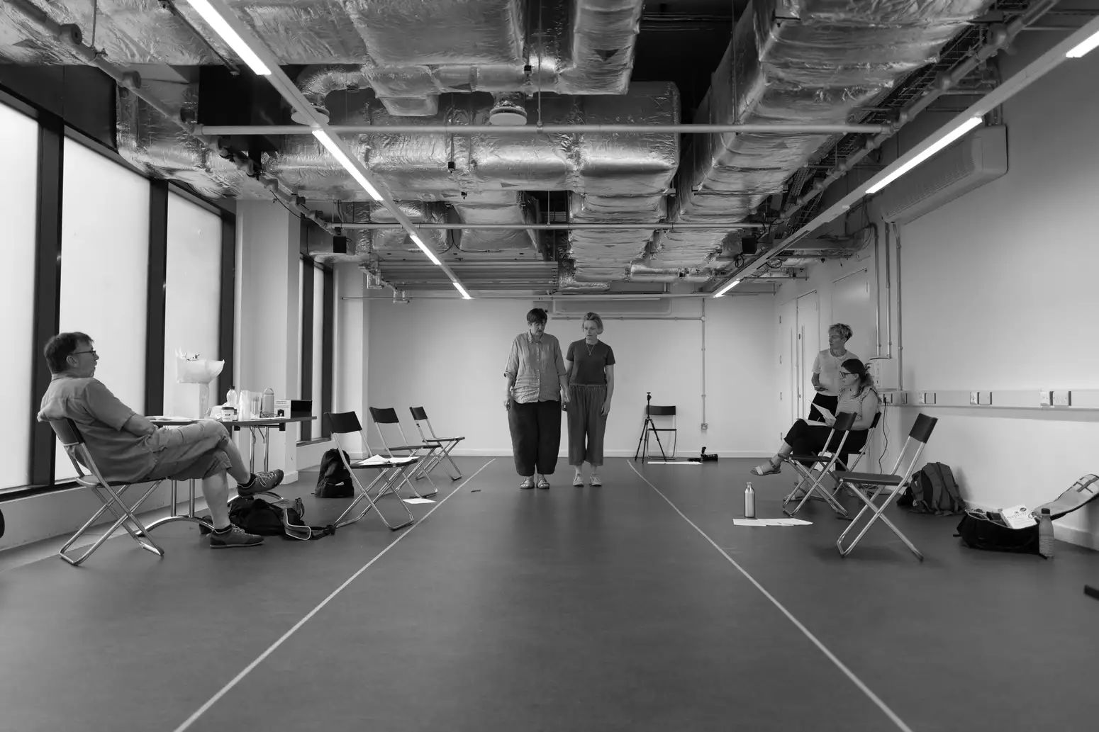 Black and white photograph of two people standing side-by-side in THEY rehearsals
