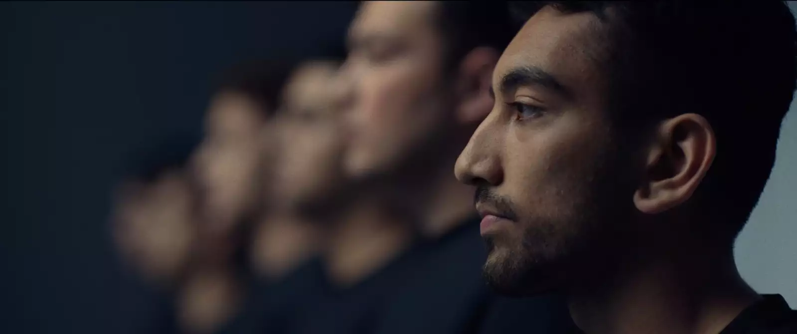 Still from In Camera. Nabhaan Rizwan stood in front of a mirror looking to the side. His blurry reflection is visible several times in the mirror.