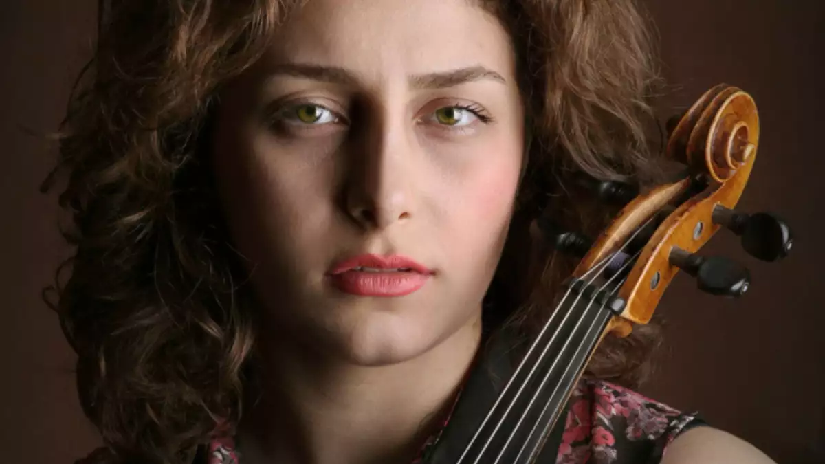 parisa prizadeh looking to camera holding a violin