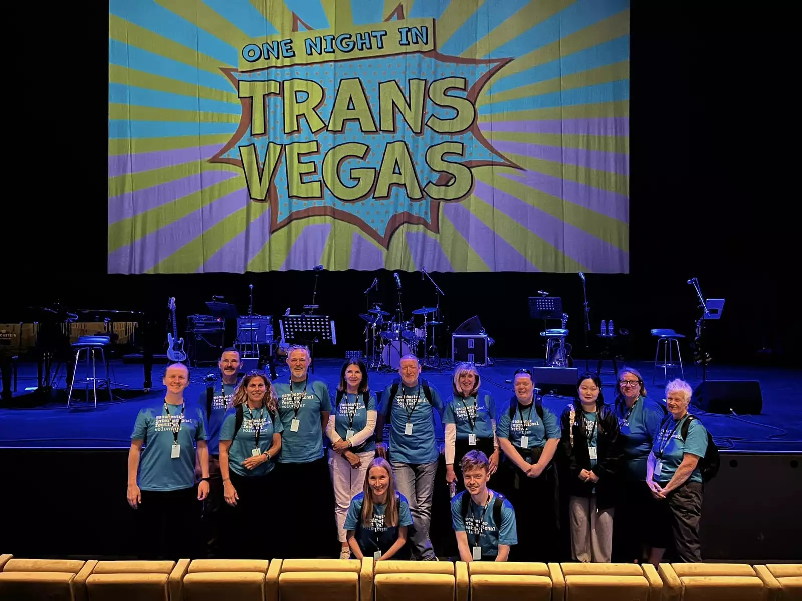 A group of volunteers in front of a screen that reads 'One Night in Trans Vegas'