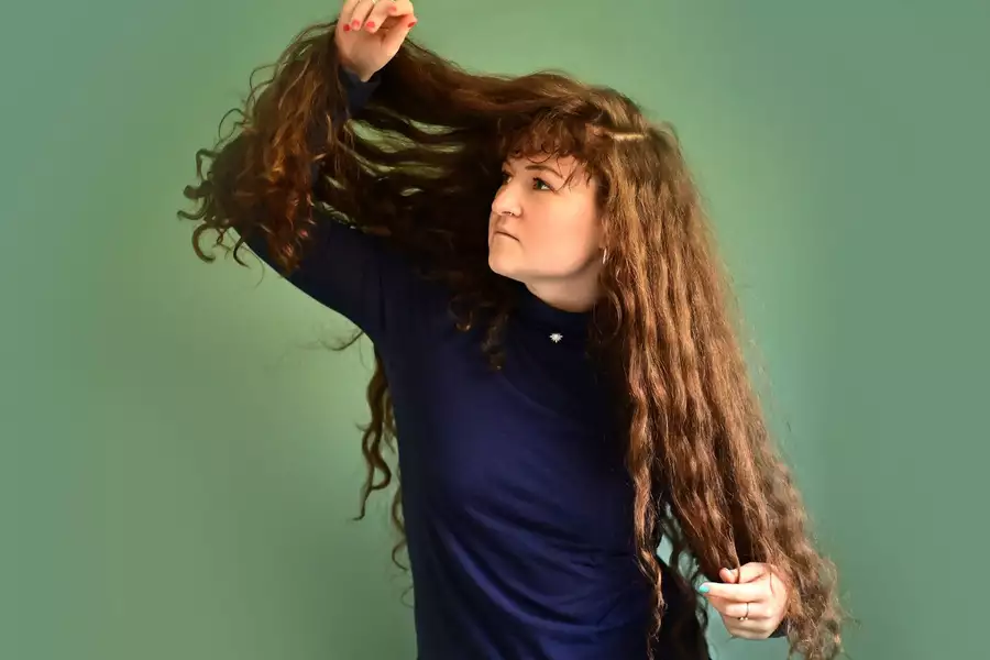 Artist Iora Holding her long curly hair up and peeking through it