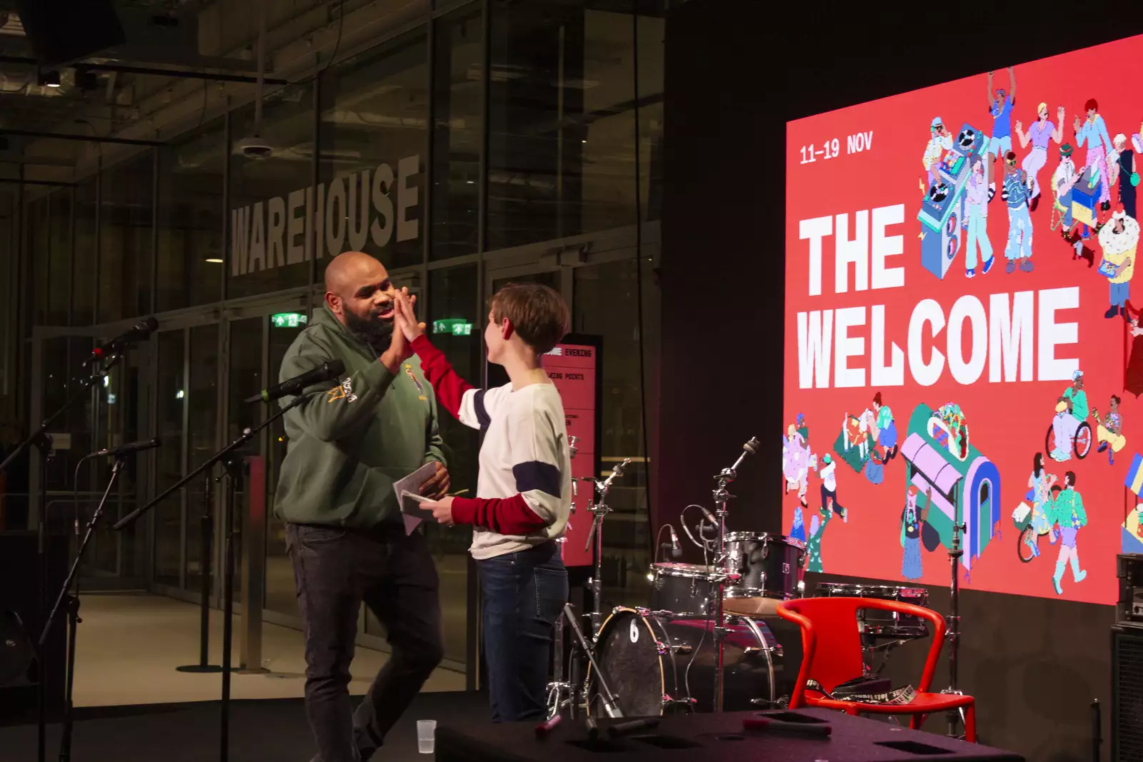 An adult and child high-five on stage during The Welcome