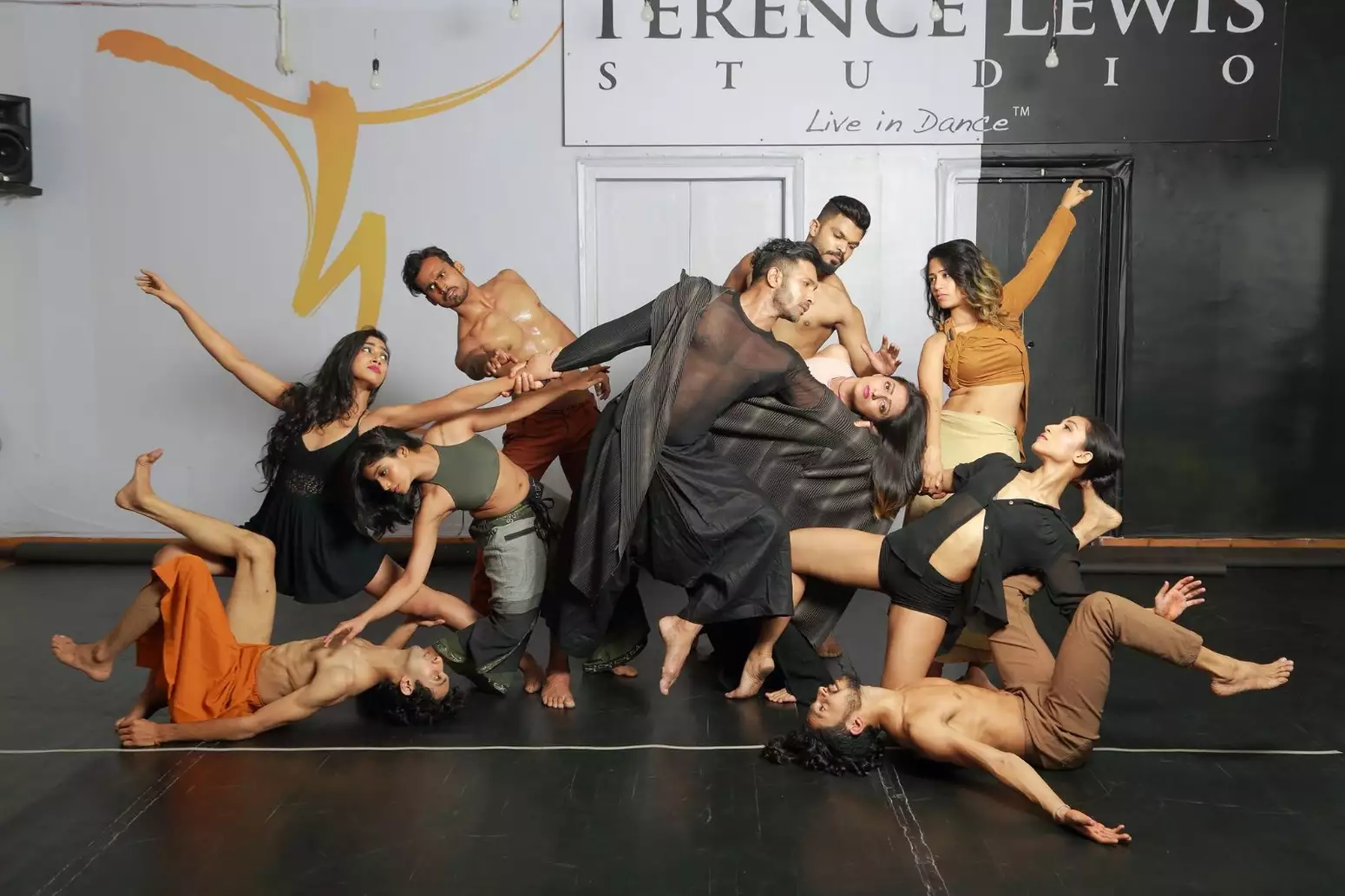 Dancers from Terence Lewis Contemporary Dance Company posing, wearing black, orange and brown clothes