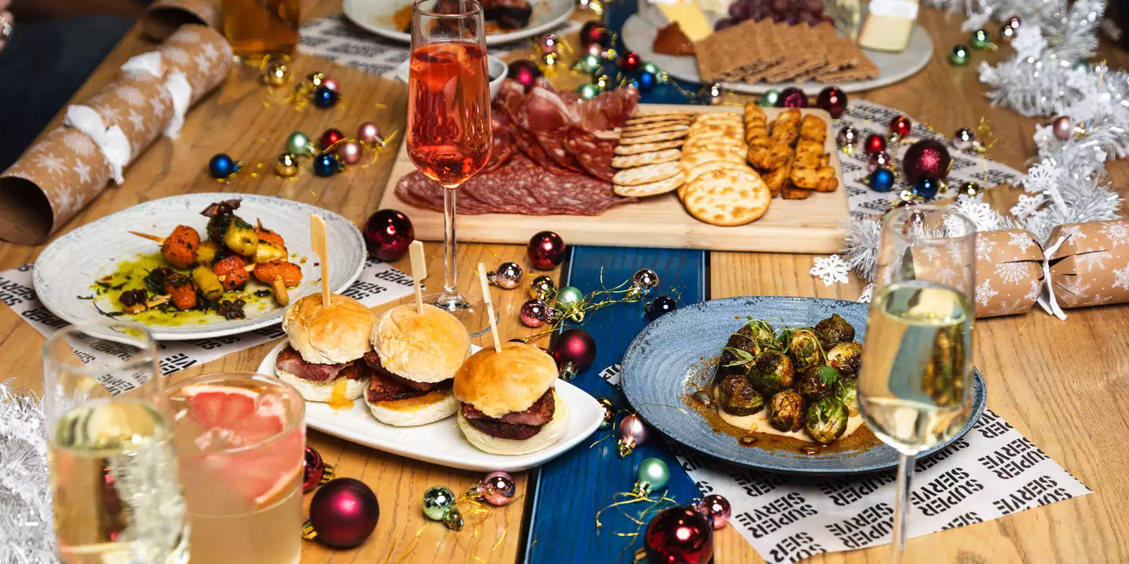 A festive table setting featuring a selection of Christmas Mezze, drinks, decorations and silver tinsel