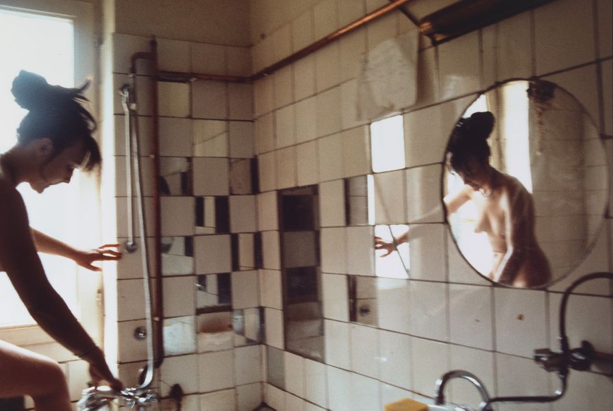 Cibachrome colour photograph of a woman in a bathroom, her reflection caught in the mirror