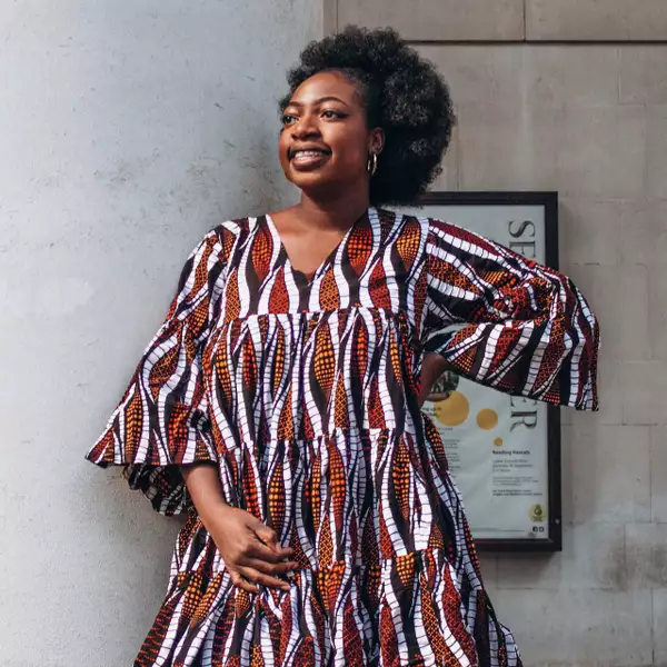 Photograph of Ronke Jane Adelakun wearing a patterned orange and red dress