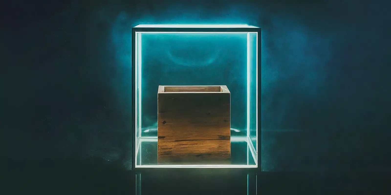 A wooden cube inside a glass and metal cube