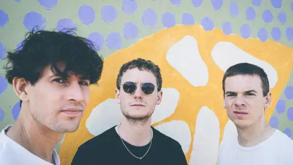 Photo of three members of Big Society in front of a colourful background