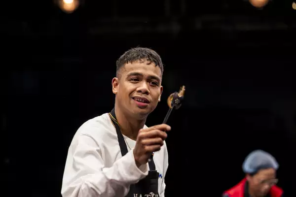 Photo of Jeff D'Sangalang on stage holding some tongs