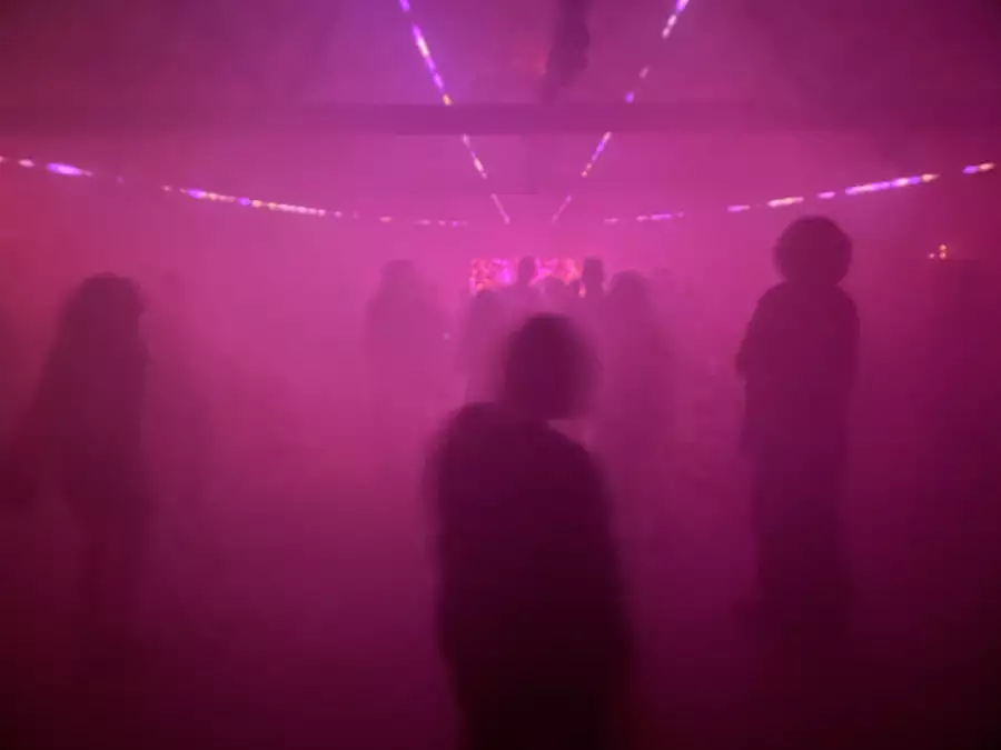 Figures on a dancefloor bathed in pink light