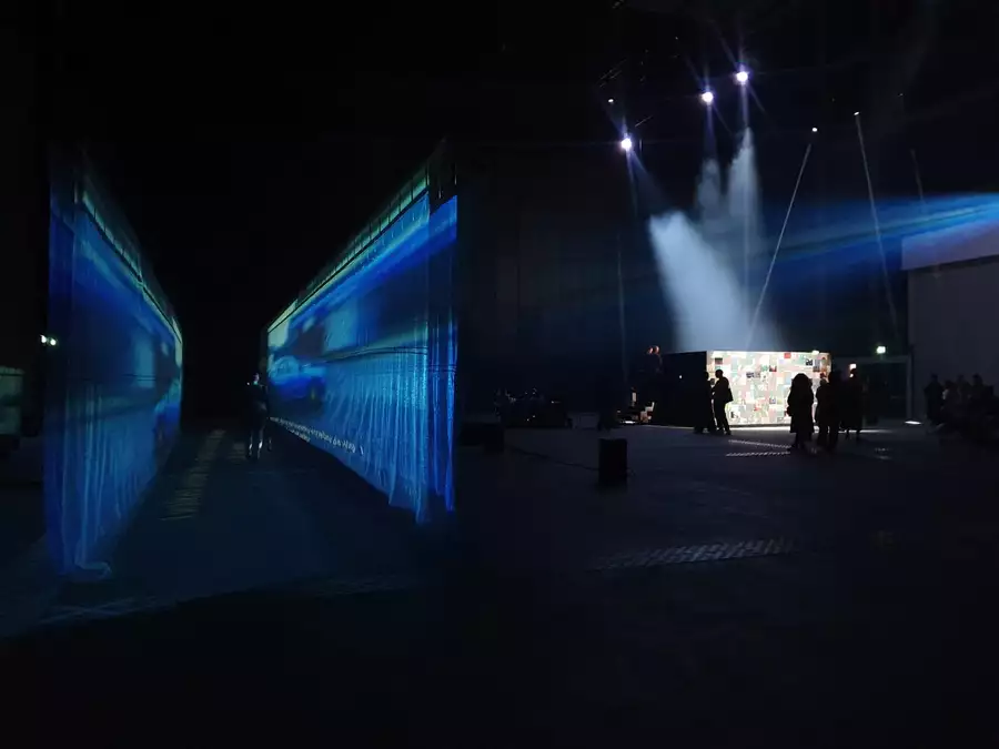 54: Manchester's installation in the warehouse – showing a fabric walkway with a film projected on to it and an enclosed, collaged box with performers inside