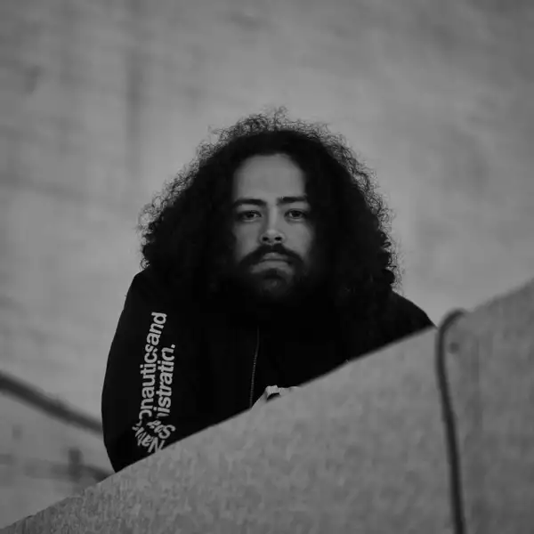 Black and white square headshot of Jack Clarke stood on stone steps wearing a black zip-up jacket