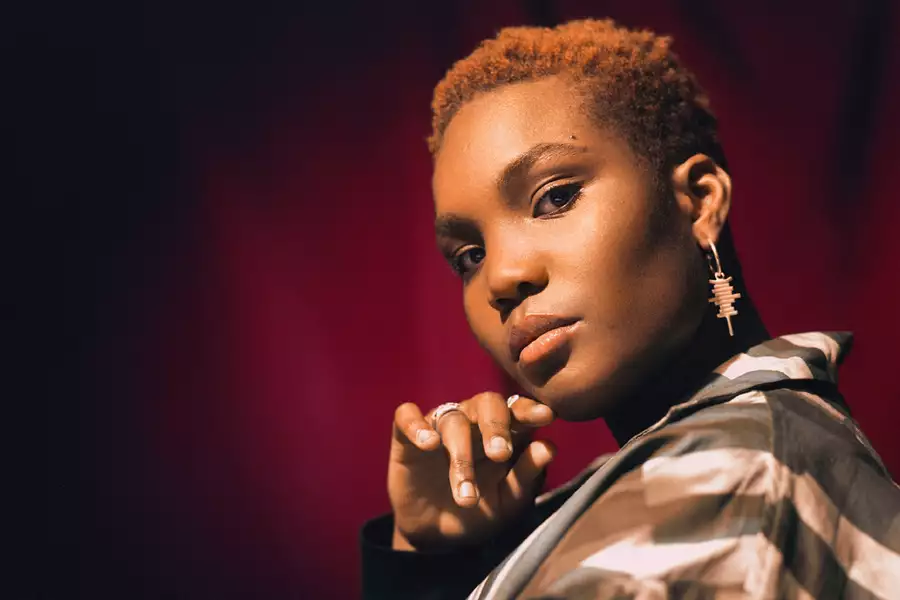 Photographic portrait of Arlo Parks on red curtain background
