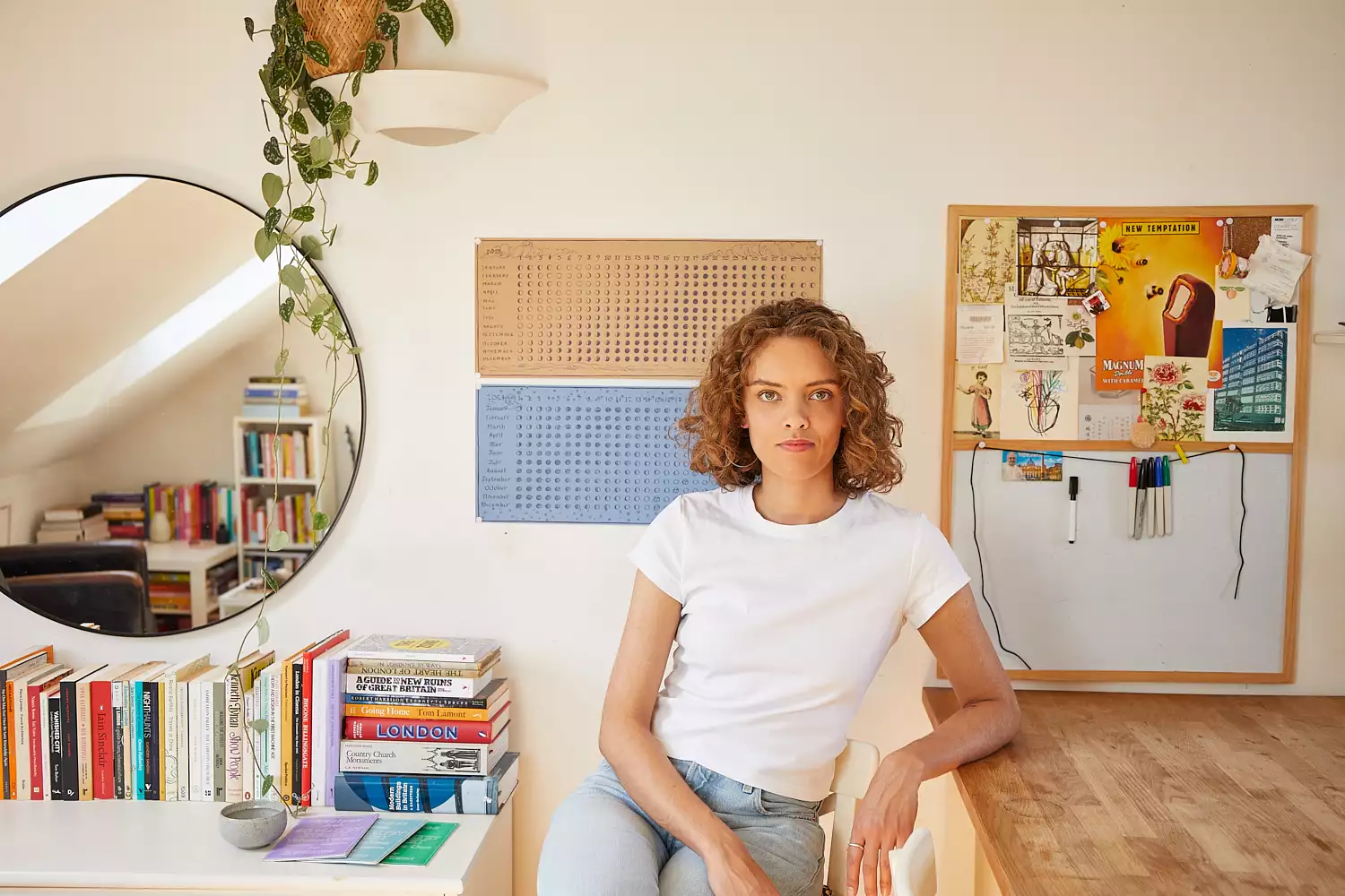 Ruby Tandoh sat at a kitchen table with a bookshelf in the background