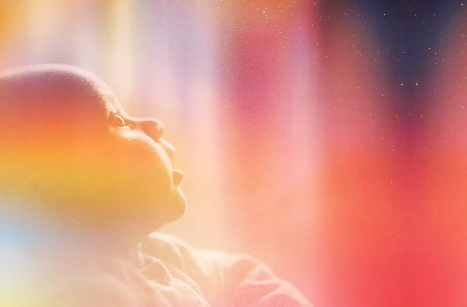 A photograph of a baby staring up in wonder at the night sky