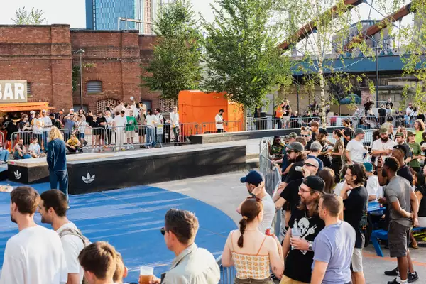 A big crowd of people outside Aviva Studios during Build Manchester. It is a sunny day.