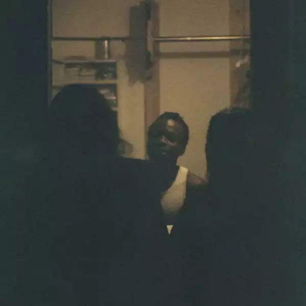 Sepia photo of Iyunoluwa Yemi-Shodimu stood between the shadows of two people