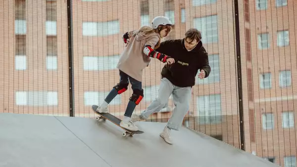 Photo of an instructor teaching a young person to skateboard on a ramp