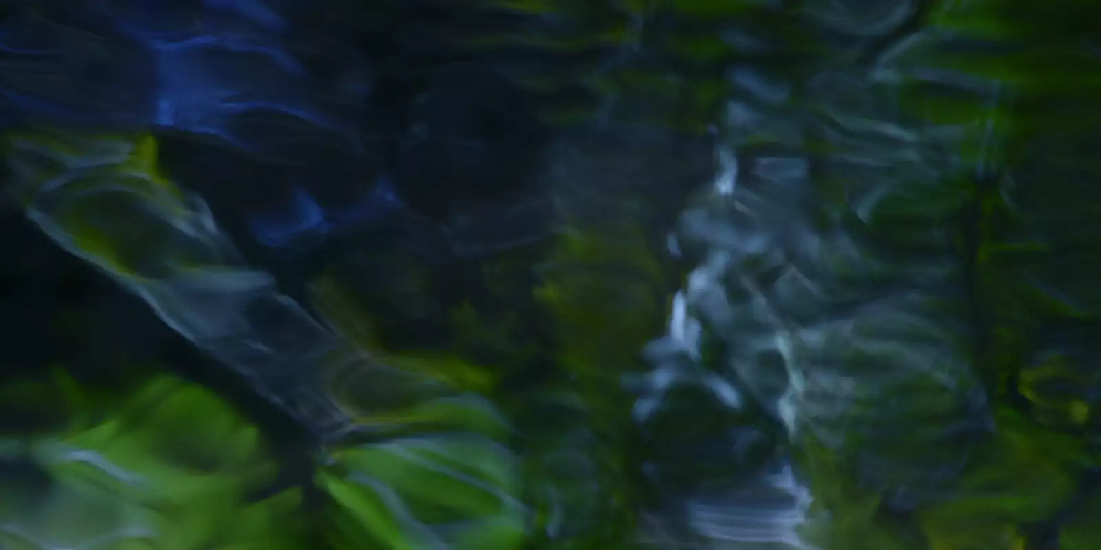 This image features a soft, abstract blend of dark blues and greens with flowing, ripple-like patterns, resembling light filtered through water or reflections on a moving surface.