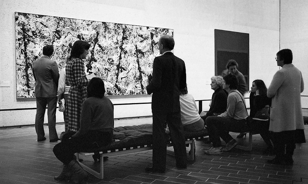 A black and white image of visitors viewing iconic painting blue poles