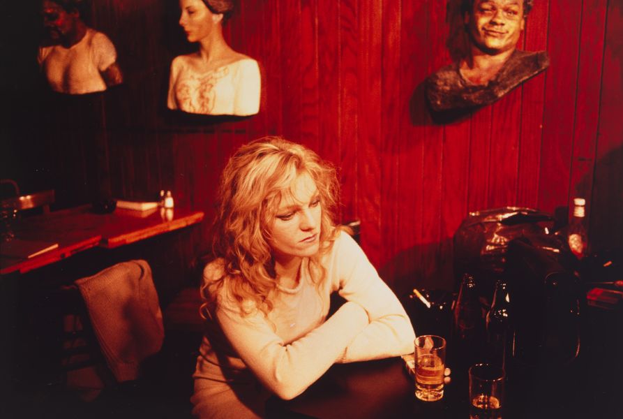 Friend of artist Nan Goldin sitting alone at a bar table.