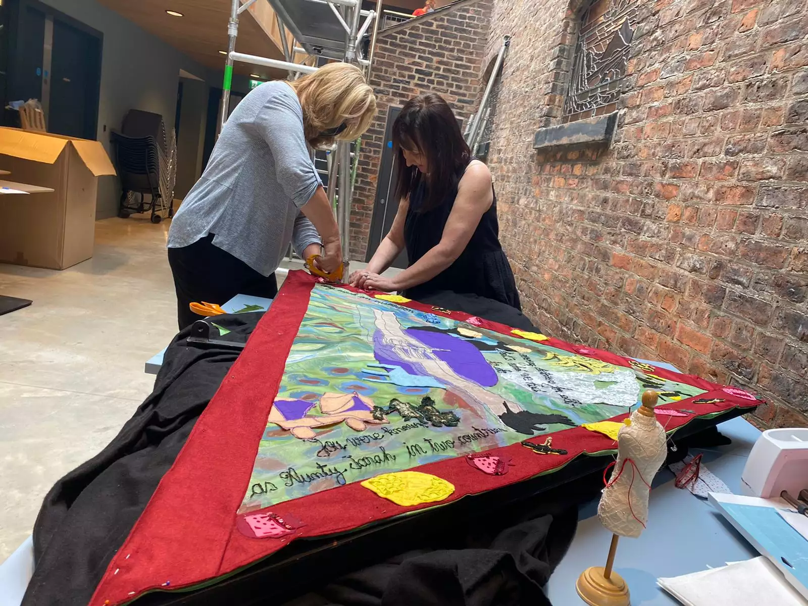 Two women from Manchester Jewish Museum textiles group assemble fabric collage.