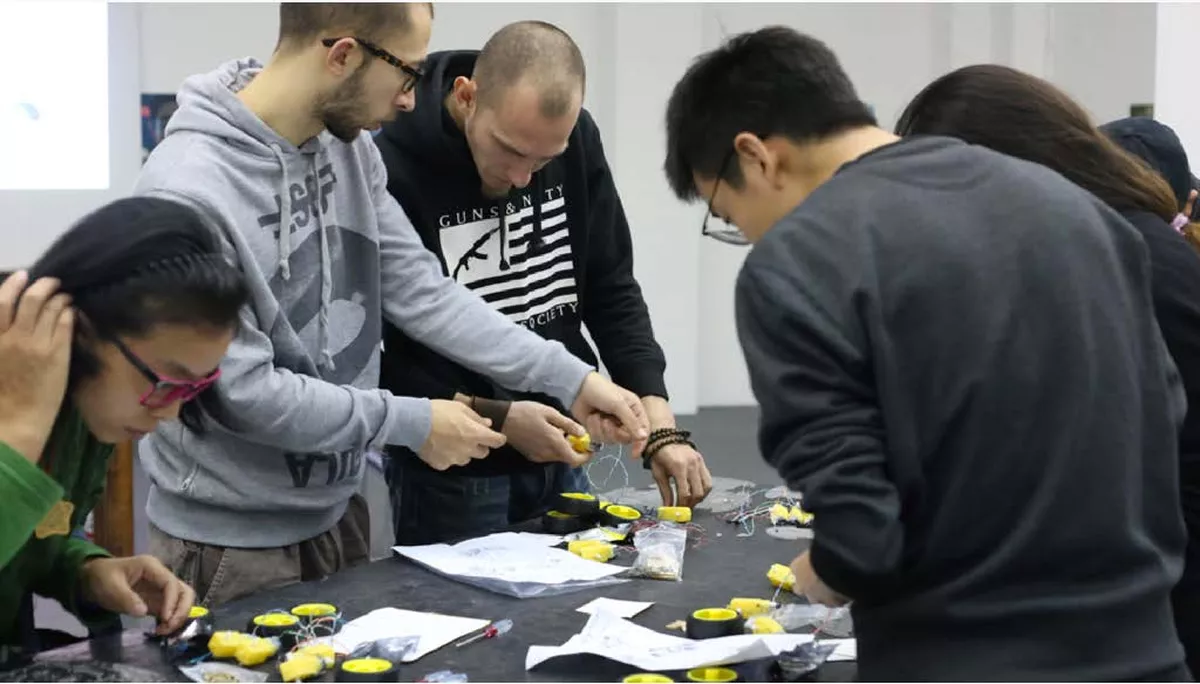 Group of people assembling robot components at a table during a workshop.