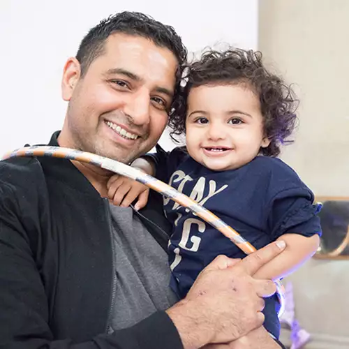 A parent and toddler smiling holding a hula-hoop