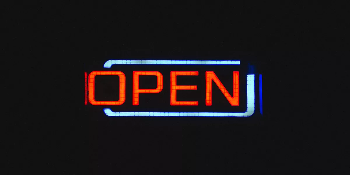 Illuminated neon sign of the word 'open' on a dark background