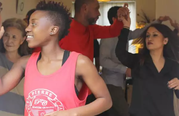 Young woman in a doorway with a group of people dancing in the room behind her