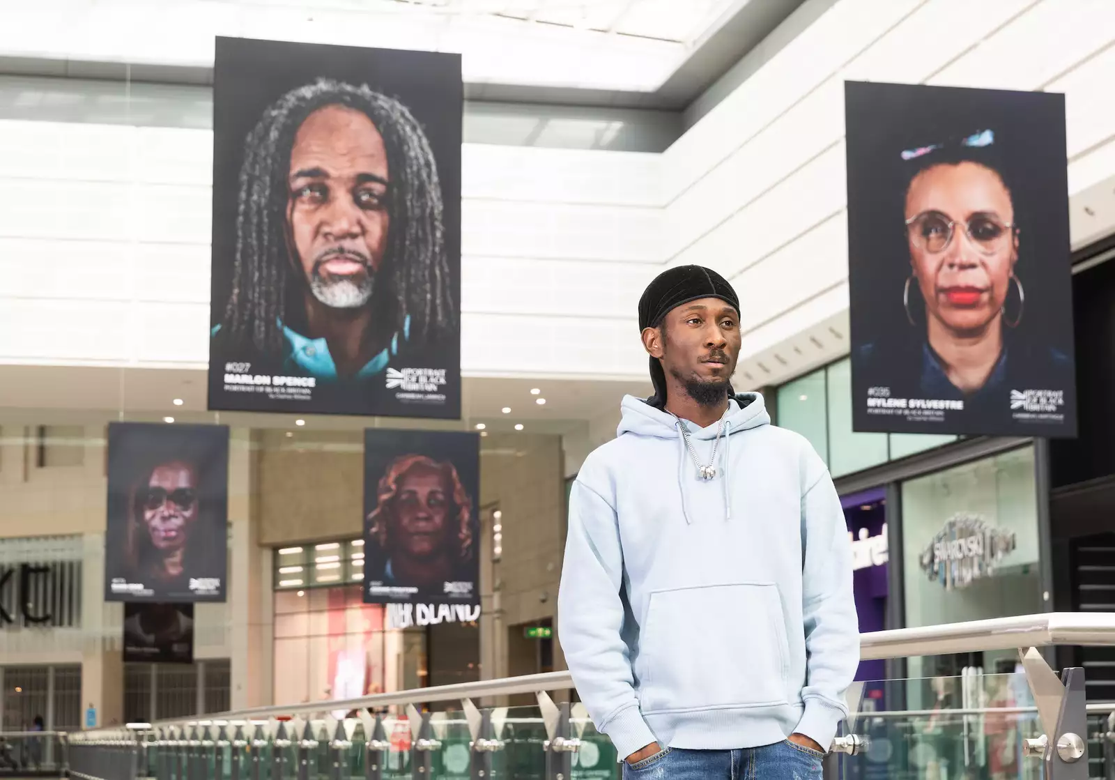 Cephas Williams is photographed standing among his photographs, which are hanging from the ceiling at the Arndale Centre in Manchester.