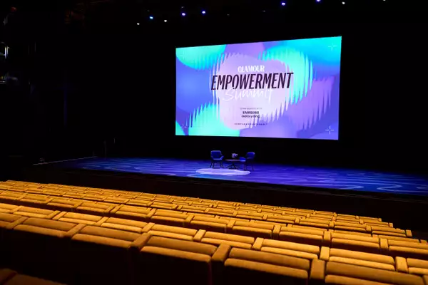 Empty seats in the Hall. The stage has two empty chairs on it ready for an event. The screen behind says 'Glamour Empowerment Summit'.