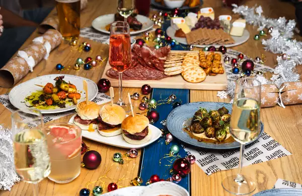A festive table setting featuring a selection of Christmas Mezze, drinks, decorations and silver tinsel