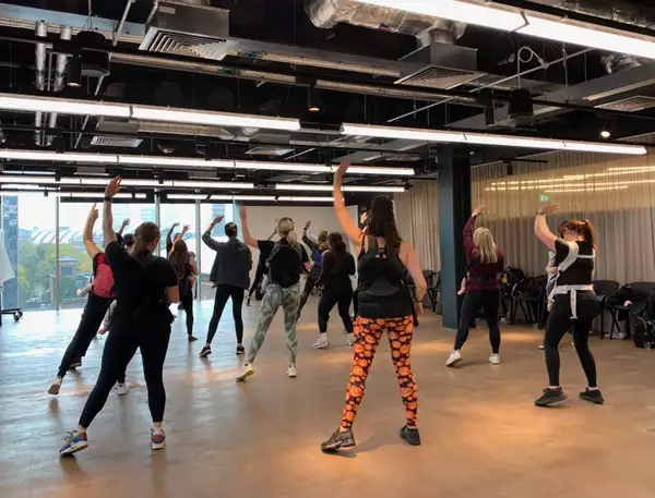 Parent/carers holding their hands in the air with their babies in slings